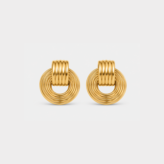 A pair of gold-toned hoop earrings with a textured, ridged circular design, shown on a light gray background.