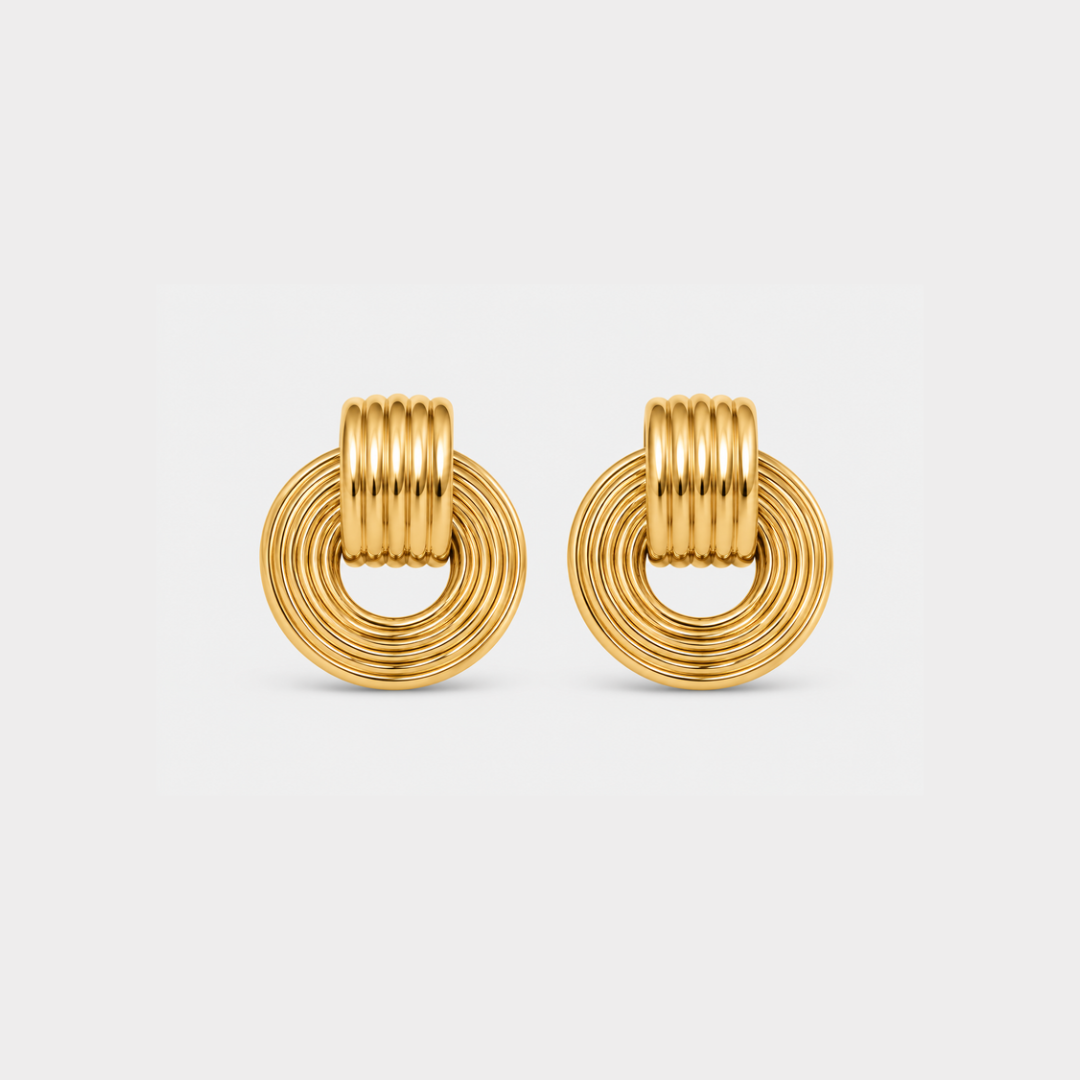 A pair of gold-toned hoop earrings with a textured, ridged circular design, shown on a light gray background.
